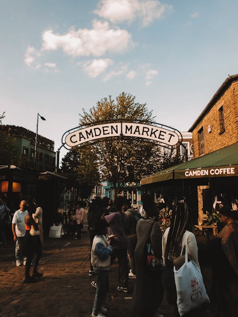 A multi-story building in Camden Town with a vibrant, painted exterior featuring various colorful murals and advertising graphics. On the facade, there is a three-dimensional sculpture of a roller ska
